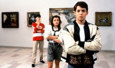 three people are standing in an art museum with paintings on the walls and one person is holding his arms crossed