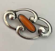 Fabulous! Beautiful sterling silver swirls define the the Art Nouveau era. The centerpiece of this brooch is an elongated cabochon natural coral. This brooch looks gorgeous pinned on a simple velvet choker.  Marked STERLING Elegant Orange Brooch Jewelry, Orange Brooch Jewelry For Formal Occasions, Formal Orange Brooch Jewelry, Elegant Orange Brooches For Gifts, Elegant Sterling Silver Brooch With Cabochon, Velvet Choker, Natural Coral, Tatting, Art Nouveau