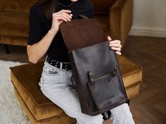 Convertible backpack briefcase: you can carry it as a cross-body bag or a rucksack. The bag is closed with a zipper, and the top opens with metal buttons that have two different positions. Wednesday wears a similar black backpack bag. There are two felt pockets inside: one for a laptop or tablet up to 13 inches, and the second one is for small essentials. The front pocket of the bag is spacious enough to fit a charger, a small wallet, a phone, a glasses case, and a mini notebook. The adjustable belt is made of rep. With high-quality hardware and carabiners, you can quickly transform the bag into a backpack. Size S: Height: 35 cm / 13.8 in Width: 25 cm / 9.8 in Bottom width: 7 cm / 2.8 in Front pocket: 20 x 15 cm / 7.9 x 5.9 in Inner pocket #1: 25 x 28 cm / 9.8 x 11.0 in Inner pocket #2: 10 Black Dark Academia, Woman Backpack, Hacks Clothes, Laptop Briefcase, Brown Purse, Trolley Bags, Convertible Backpack, Brown Purses, Fashion Hacks