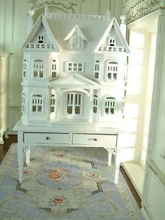 a large white doll house sitting on top of a wooden table next to a doorway