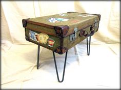 an old suitcase with stickers on it is sitting on some hairpin legs and has been turned into a stool