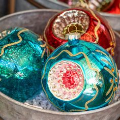 three glass ornaments in a metal bowl