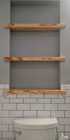 a white toilet sitting in a bathroom next to a shelf with shelves on it's sides