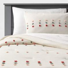 a bed with white sheets and red flowers on it