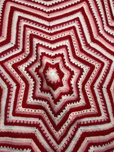 a red and white crocheted afghan is shown in the shape of a star