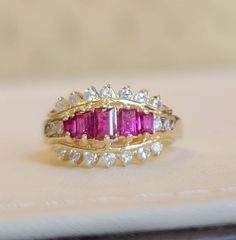 This is a 14kt yellow gold Ruby and diamond ring. Five pieces of straight baguette cut rubies total weight 0.89 carats. 18 pieces of small diamonds total weight 0.40 carats 14kt yellow gold ring weight 4.2 grams. Baguette Cut Ruby Yellow Gold Jewelry, Yellow Gold Ruby Baguette-cut Jewelry, Luxury Gold Ruby Ring With Single-cut Diamonds, Diamond And Ruby Ring, Vintage 14k Gold Multi-stone Ruby Ring, Luxury Multi-stone Ruby Ring In 14k Gold, Ruby And Diamond Ring, Butterfly Bracelet, Red Band