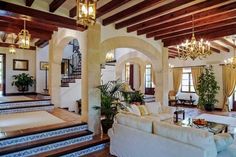 a living room filled with furniture and a chandelier hanging from the rafters