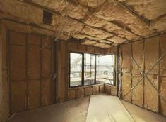 an unfinished room with wooden walls and windows