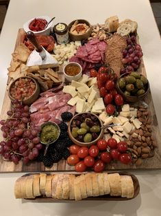 an assortment of meats and cheeses on a cutting board with breadsticks