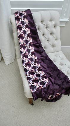 a white chair with a purple flowered blanket on it