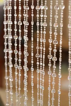 beads hanging from the ceiling in front of a window with raindrops on it