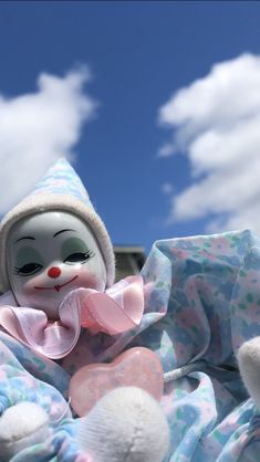 a stuffed animal that is laying down on a blanket with clouds in the sky behind it