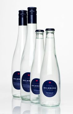 three bottles of water sitting next to each other on a white surface with one empty bottle in the foreground