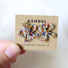 a person holding up a small card with beads on it