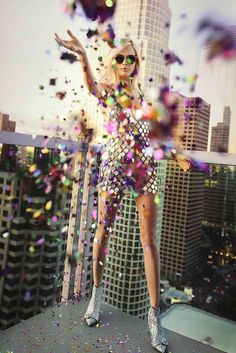 a woman standing on top of a building with confetti all over her body