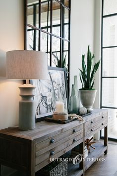 a table with a lamp, vases and pictures on it in front of a mirror