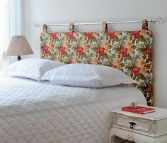 a bed with white linens and floral headboard