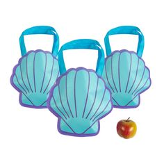 three blue plastic bags with handles and an apple on the ground next to each other