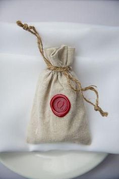 a bag with a wax seal on it sitting on top of a white table cloth