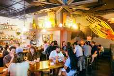 a group of people sitting at tables in a restaurant with food and drinks on the walls