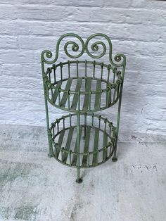 an old green metal magazine rack sitting on the side of a white brick wall with peeling paint