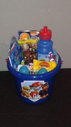 a blue plastic basket filled with toys on top of a table next to a wall