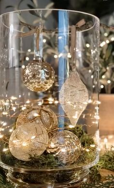 a glass vase filled with christmas ornaments on top of a table