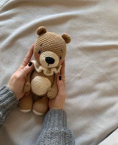 a person holding a teddy bear on top of a bed