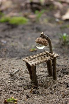 a miniature wooden bench with a glass ball sitting on it's seat in the dirt