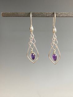 "Romantic and flirty Amethyst earrings are sure to enhance any outfit in your wardrobe. Deep purple Amethyst stones are bezel set in Sterling silver, hangs within a Sterling silver charm and Sterling silver ear wires. These lightweight earrings hang 1.75-inches and swing lightly in the breeze. A wonderful gift for someone born in February since Amethyst is their birthstone! Arrives in a standard gift box. FOR GIFT GIVING: ** Satin gift pouch with note card and upgraded jewelry box is also availa Plum Jewelry, Amethyst Earrings For Party, Elegant Amethyst Teardrop Dangle Earrings, Purple Sterling Silver Earrings For Party, Elegant Purple Dangle Chandelier Earrings, Handmade Amethyst Chandelier Earrings, Handmade Elegant Amethyst Chandelier Earrings, Elegant Amethyst Chandelier Earrings For Gift, Elegant Nickel-free Purple Earrings