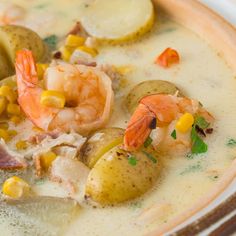 a bowl of soup with shrimp, potatoes and corn