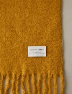 an orange scarf with fringes on it and a label that says luluu - gordaia