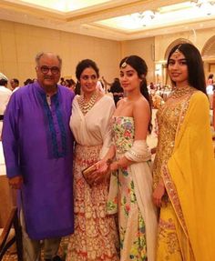 three women and one man standing next to each other in formal wear at an event