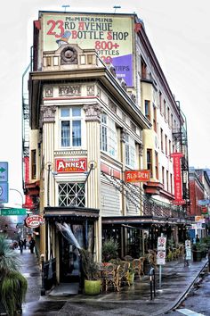 an old building on the corner of a city street with people walking by in the rain