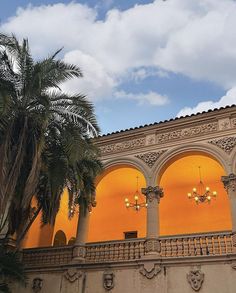 an ornate building with chandeliers and palm trees in the foreground at dusk