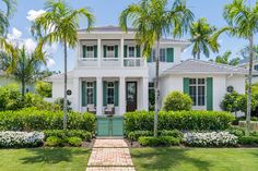 a white house with green shutters and palm trees