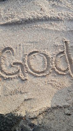 the word god written in sand on a beach