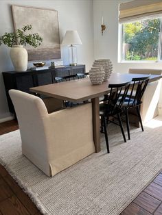 a dining room table and chairs in front of a window with a rug on the floor