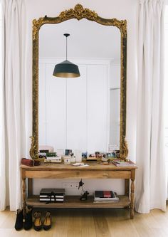 a mirror sitting on top of a wooden table next to a pair of shoes in front of a window