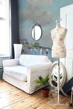 a white couch sitting next to a mirror on top of a wooden floor