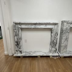 two white marble fireplaces sitting on top of a hard wood floor