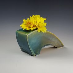 a green vase with yellow flowers in it