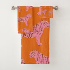 two towels hanging on a towel rack in front of an orange background with white tigers