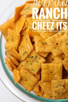 a bowl filled with cheetos sitting on top of a white table next to a glass plate