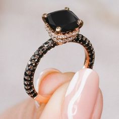 a close up of a person's hand holding a black and white diamond ring