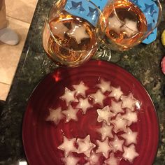 a red plate topped with stars next to two wine glasses