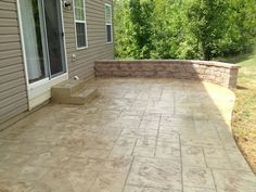 an outdoor patio with stone steps and brick pavers around the back door, in front of a house