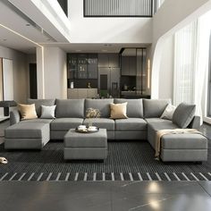 a modern living room with gray couches and pillows on the floor in front of a large window