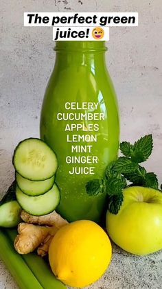 a green juice bottle sitting next to cucumbers and lemons