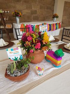 a table topped with potted plants on top of a white tablecloth covered table